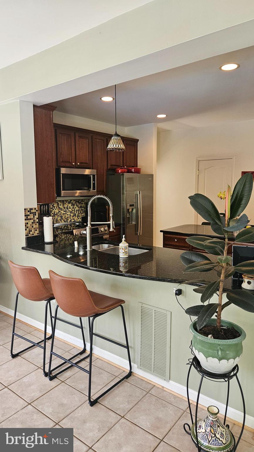 6107 Traceys Overlook Road Tracys Landing, MD 20779 - Photo 6 of 67 a kitchen with stainless steel appliances kitchen island granite countertop a table chairs in it and wooden floors