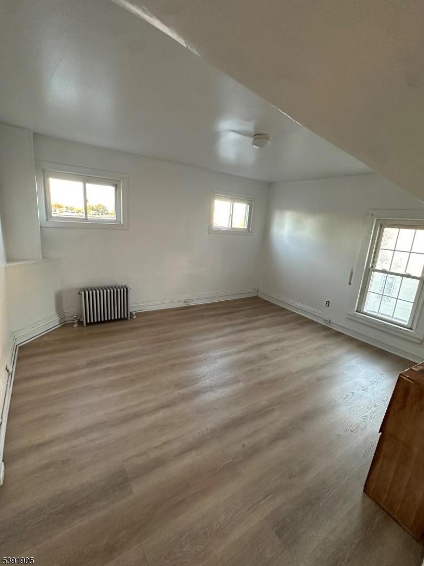421 Ellison Street Paterson, NJ 07501 - Photo 5 of 12 an empty room with wooden floor and windows