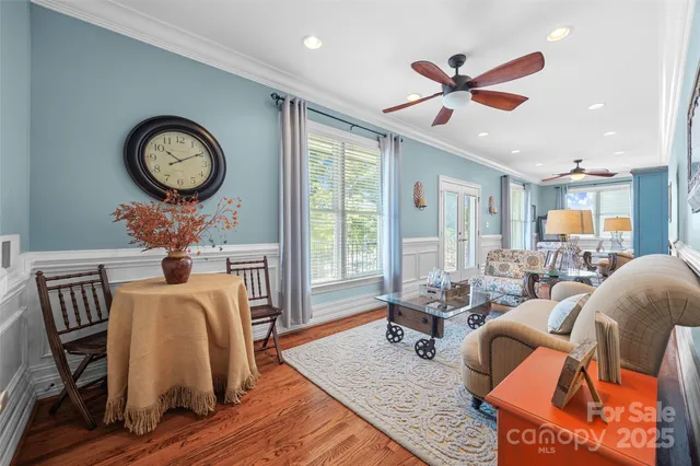 a view of a livingroom with furniture wooden floor a ceiling fan and windows