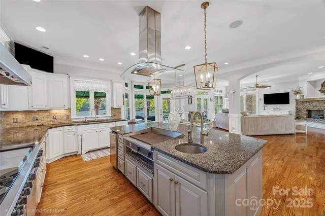 a kitchen with stainless steel appliances granite countertop a sink a stove and a wooden floors