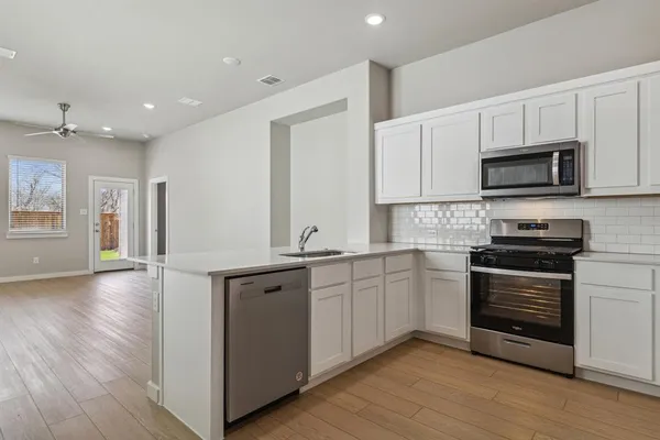 a kitchen with stainless steel appliances granite countertop a stove top oven a sink and white cabinets