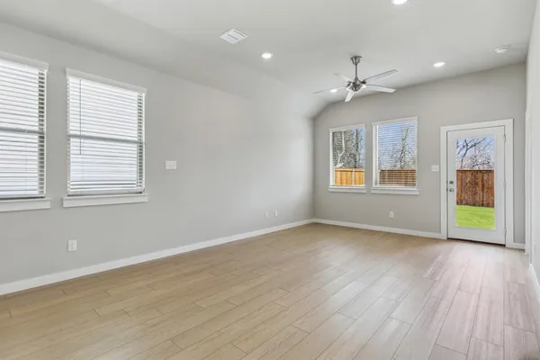 a view of an empty room with a window and wooden floor