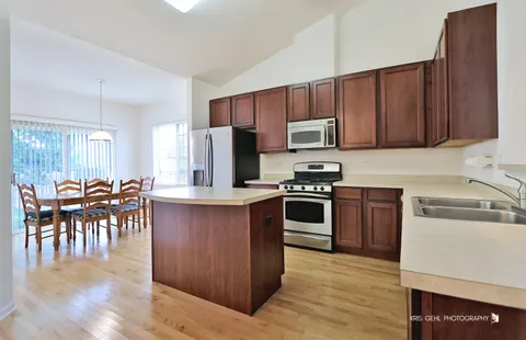 a kitchen with kitchen island granite countertop wooden cabinets a stove a microwave a island with a dining table and chairs