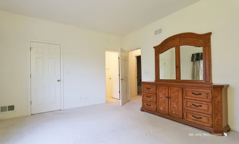 a spacious bedroom with a bed and a dresser