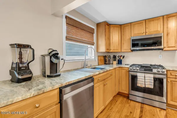 a kitchen with kitchen island granite countertop a sink cabinets and stainless steel appliances