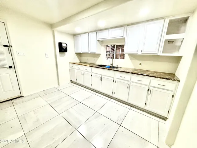 a kitchen with granite countertop white cabinets white appliances a sink and a refrigerator