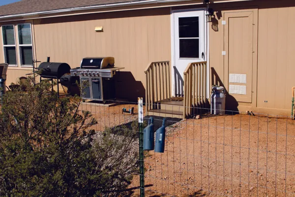 a view of a dry yard with trees in the background