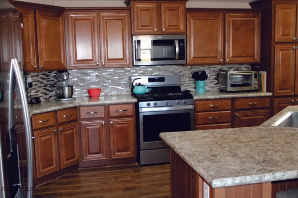 a view of a kitchen with refrigerator and wooden floor