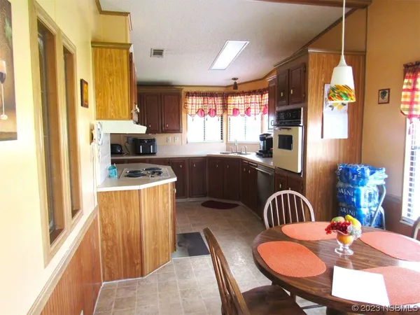 a kitchen with stainless steel appliances kitchen island granite countertop a table chairs and a refrigerator