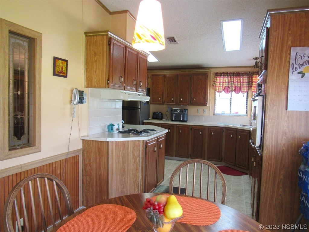 4347 Cedar Way Edgewater, FL 32141 - Photo 9 of 32 a kitchen with stainless steel appliances granite countertop a refrigerator a stove a sink dishwasher and wooden cabinets with wooden floor