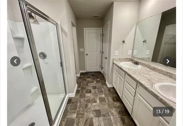 a bathroom with double vanity and a mirror