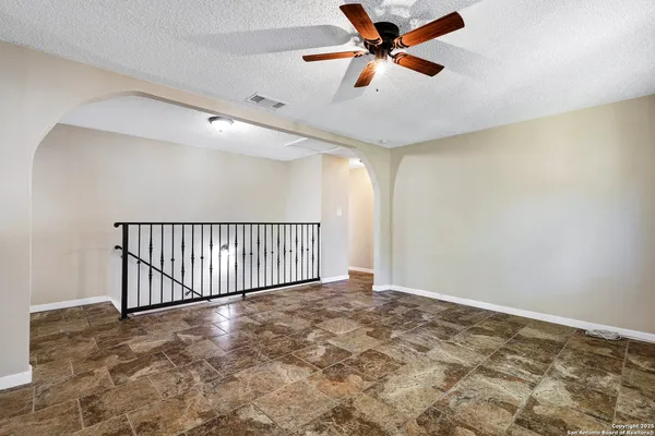 an empty room with wooden floor fan and windows