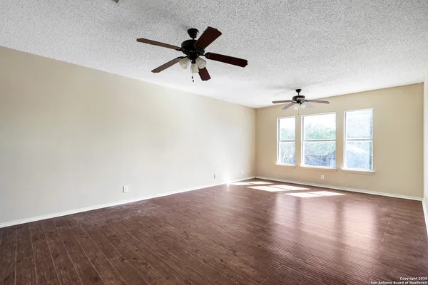 a view of an empty room with window and wooden floor