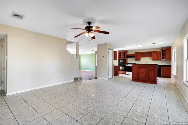 a view of an empty room with a window and kitchen view