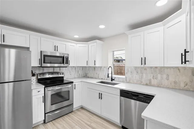 a kitchen with cabinets stainless steel appliances and wooden floor
