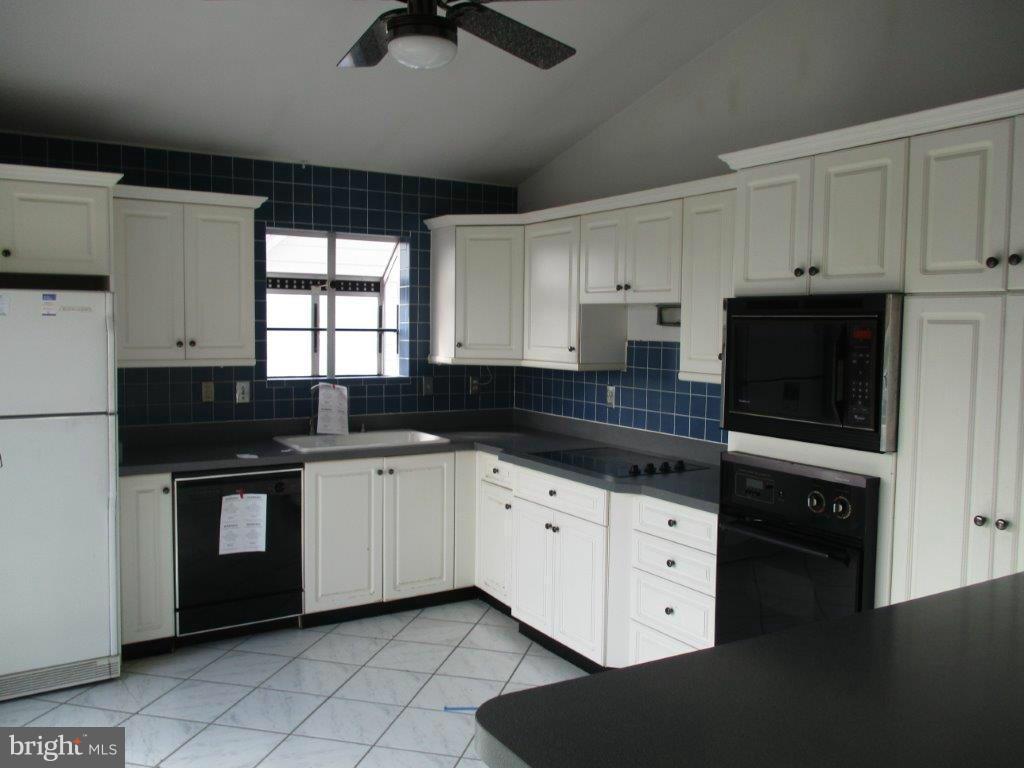 3223 Lynch Road Baltimore, MD 21219 - Photo 6 of 15 a kitchen with granite countertop white cabinets and black appliances