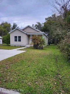 a view of a house with a yard and large trees