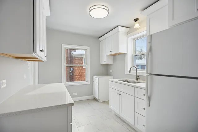 a kitchen with white cabinets and sink