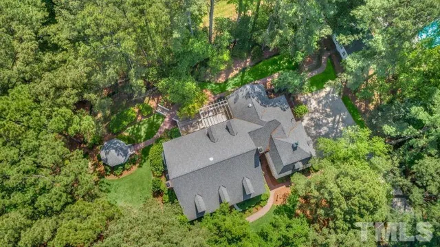 an aerial view of residential house with outdoor space and trees all around