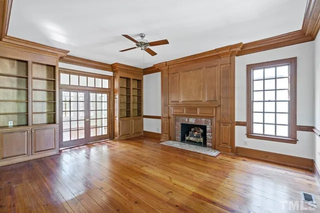 a view of an empty room with wooden floor fireplace and a window