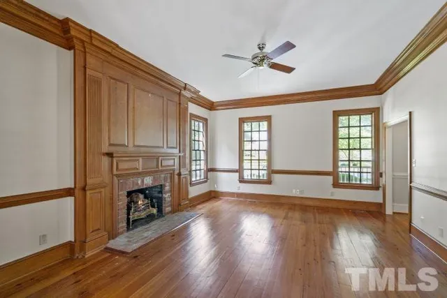 a view of empty room with wooden floor and fan