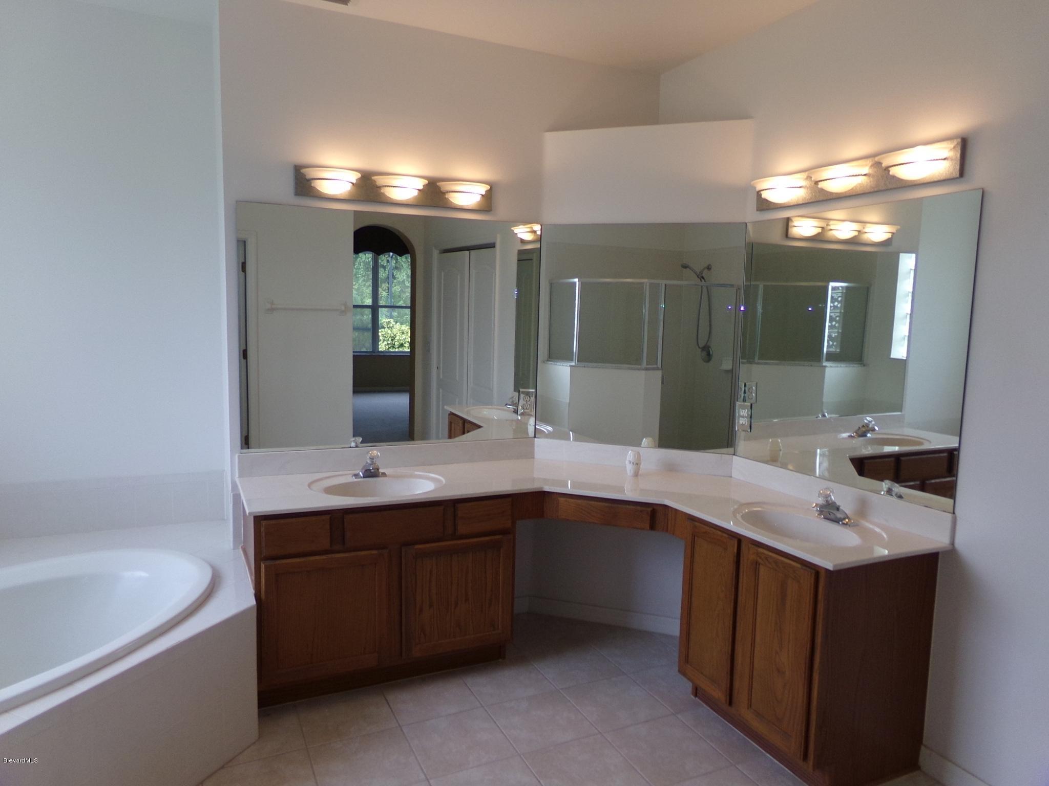 3995 Harlock Road Melbourne, FL 32934 - Photo 18 of 34 a bathroom with a sink double vanity granite tub and a mirror