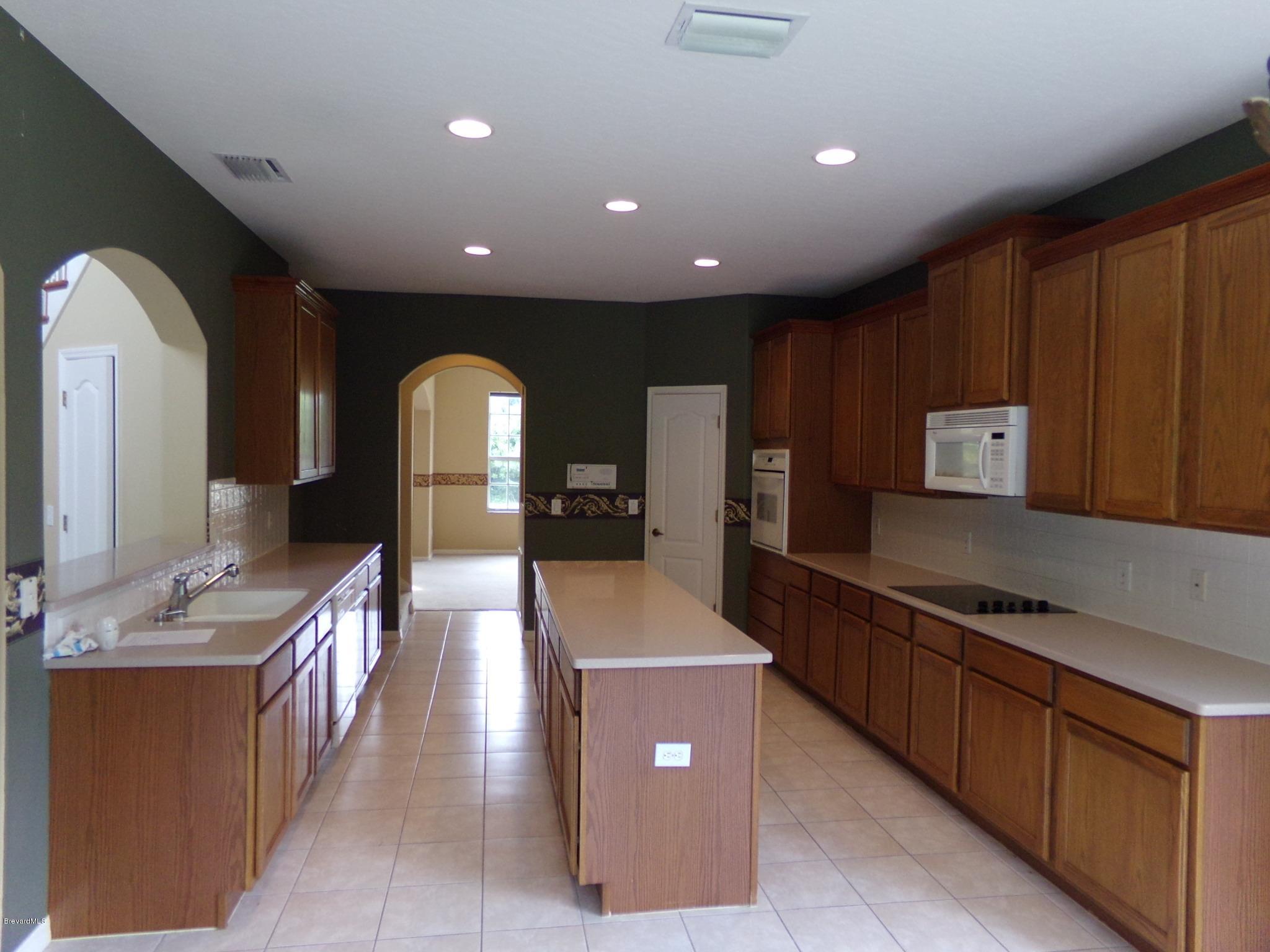 3995 Harlock Road Melbourne, FL 32934 - Photo 6 of 34 a large kitchen with stainless steel appliances a large counter top a stove and a refrigerator