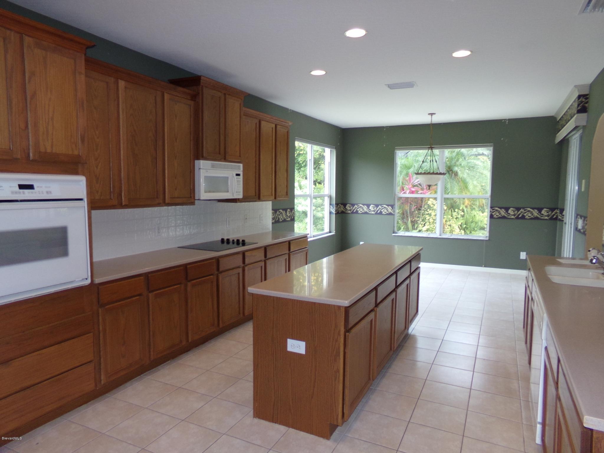 3995 Harlock Road Melbourne, FL 32934 - Photo 7 of 34 a kitchen with kitchen island granite countertop wooden cabinets a sink and a window