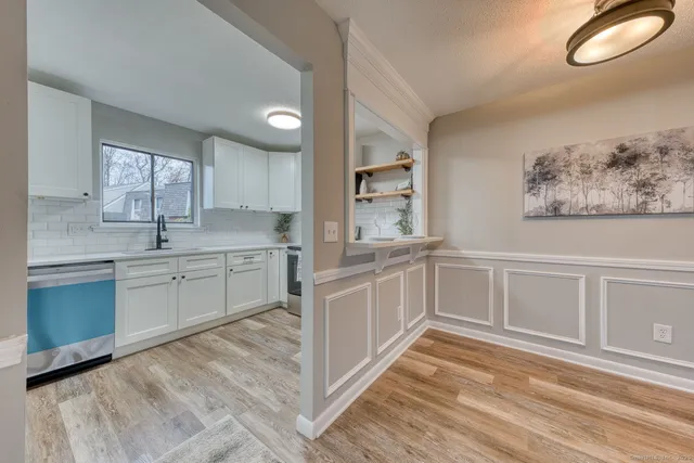 a kitchen with white cabinets and window