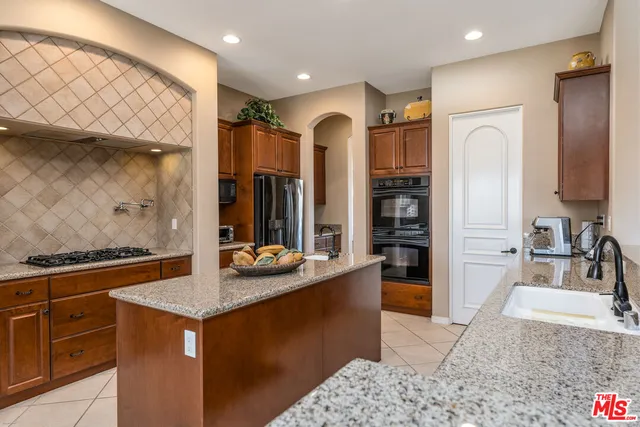 a kitchen with stainless steel appliances granite countertop a sink and a refrigerator
