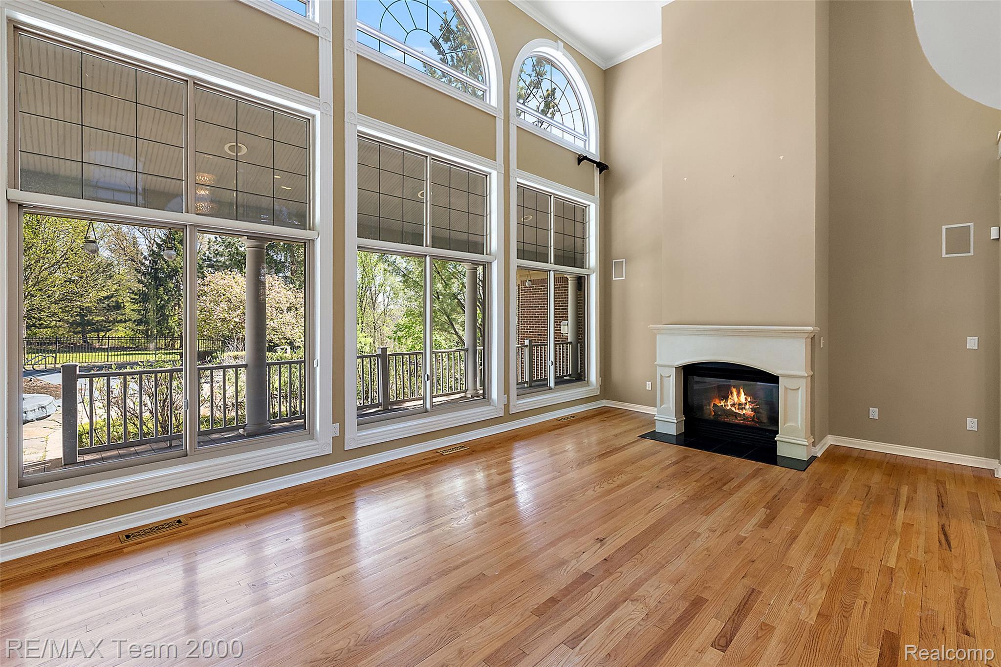 630 Sheldon Court Rochester, MI 48306 - Photo 17 of 94 Unfurnished living room featuring a fireplace with flush hearth, light wood-style flooring, a high ceiling, and crown molding