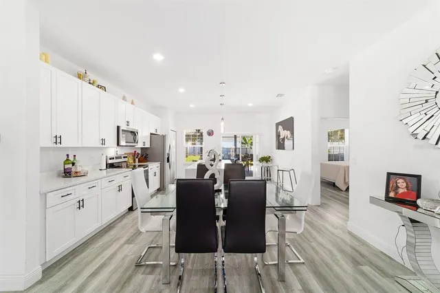 a kitchen with stainless steel appliances a refrigerator a sink dishwasher a stove with white cabinets and wooden floor