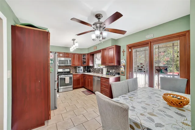 a large open kitchen with stainless steel appliances granite countertop a refrigerator a oven a dining table and chairs with the large windows