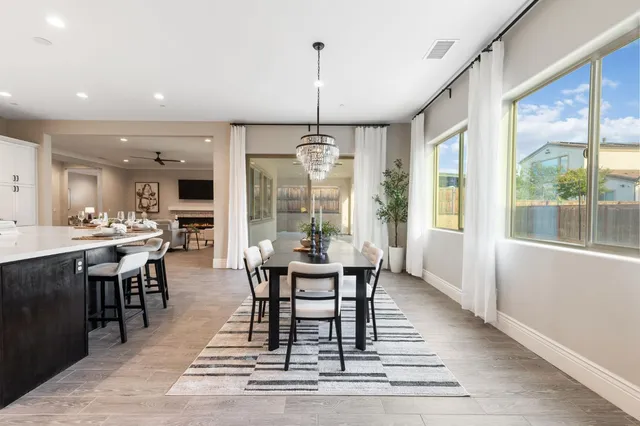 a dining room with wooden floor a chandelier a wooden table and chairs