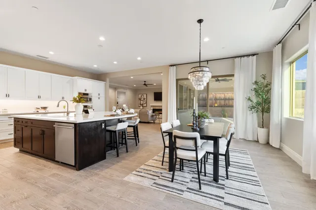 a view of a dining room and livingroom with furniture wooden floor a chandelier