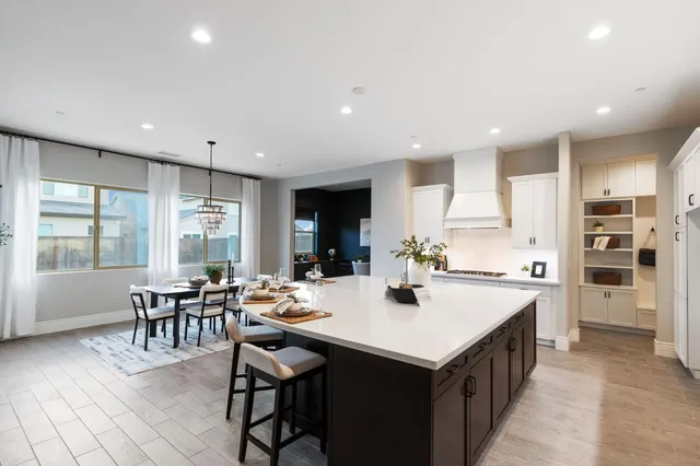 a kitchen with a dining table chairs and white appliances