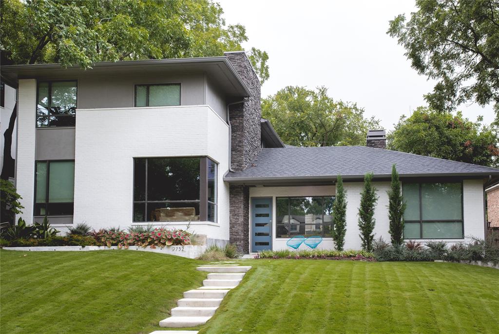 a view of a yard in front of a house with plants and large tree
