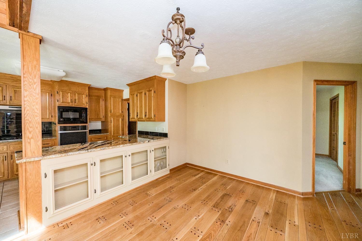 1796 Union Church Road Thaxton, VA 24174 - Photo 44 of 83 a kitchen with stainless steel appliances granite countertop a sink dishwasher a stove top oven a dining table and chairs with wooden floor
