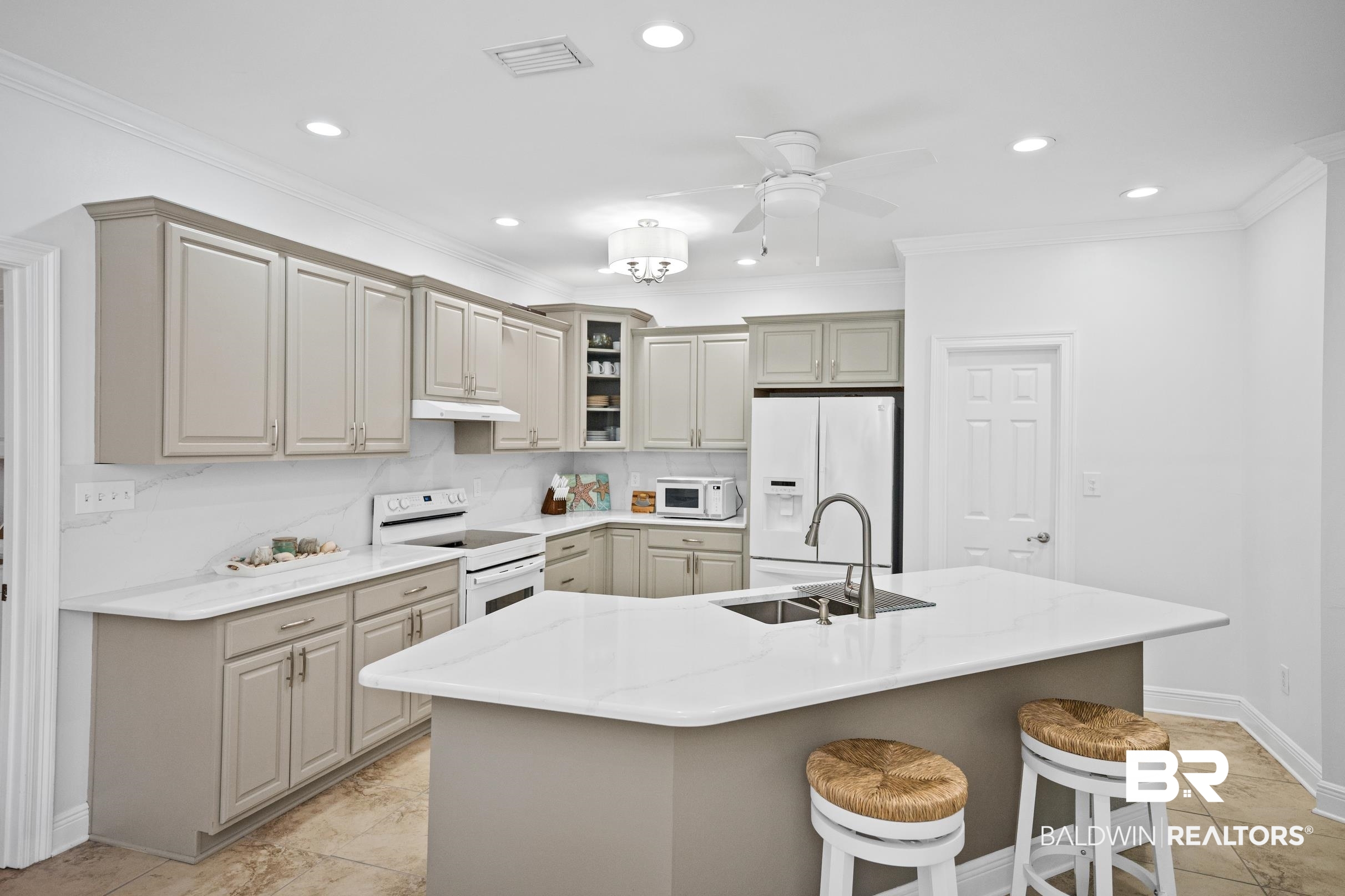 5217 Greentree Road Orange Beach, AL 36561 - Photo 16 of 58 Kitchen with white appliances, crown molding, a kitchen island with sink, a breakfast bar, and recessed lighting