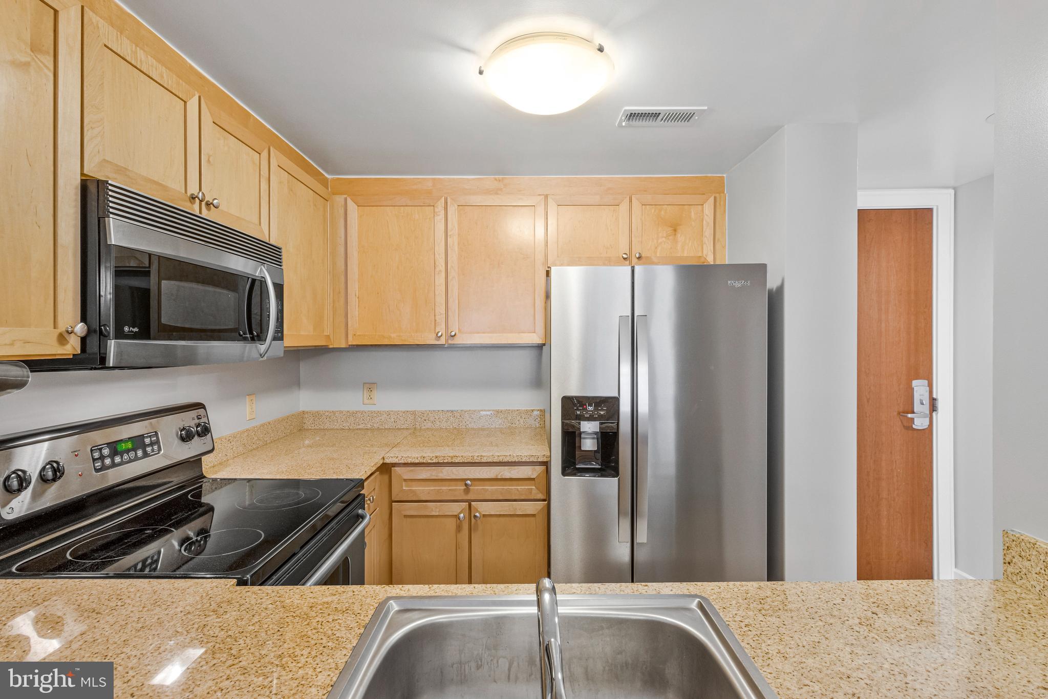 1150 K Street Northwest, Unit 1307 Washington, DC 20005 - Photo 17 of 29 a kitchen with granite countertop a refrigerator and a stove top oven