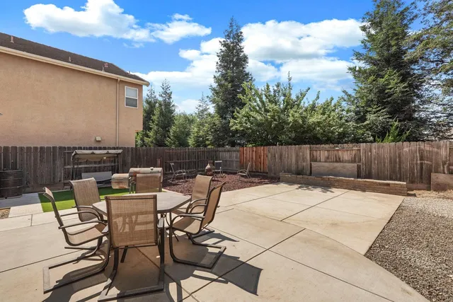 a view of backyard with seating space and wooden fence