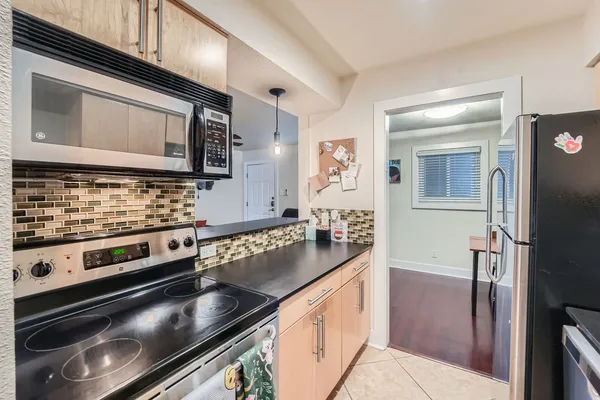 a view of a hallway with wooden floor and a refrigerator in a kitchen