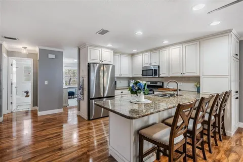a kitchen with stainless steel appliances granite countertop a refrigerator a stove a sink a dining table and chairs