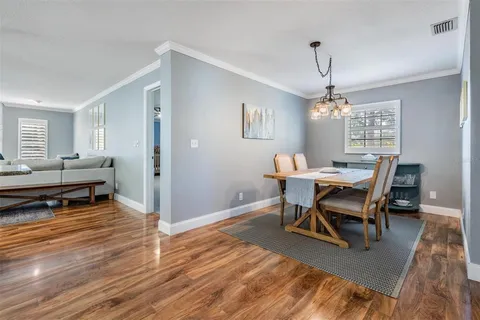 a dining room with wooden floor a chandelier a wooden table and chairs