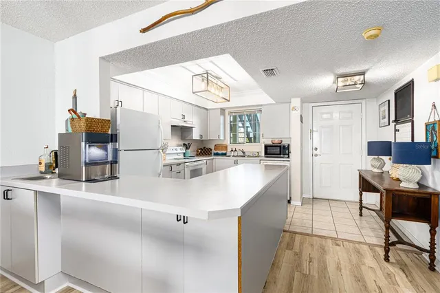 a kitchen with stainless steel appliances kitchen island granite countertop a refrigerator a stove and a sink with cabinets