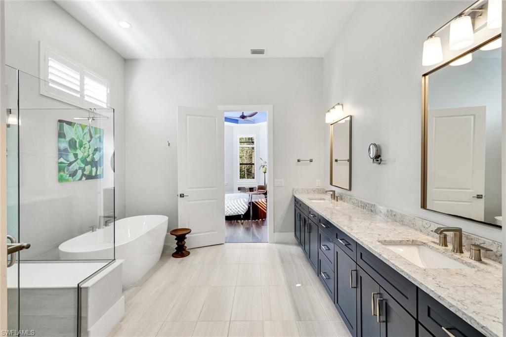 16249 Verilyn Circle Naples, FL 34110 - Photo 20 of 48 a spacious bathroom with a granite countertop double vanity sink a mirror and a bathtub