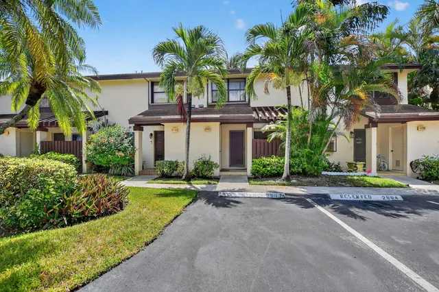 front view of house with a yard and palm trees