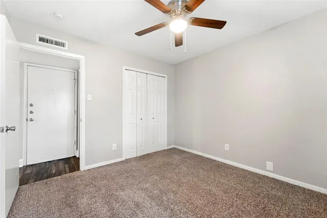 an empty room with closet and a chandelier fan