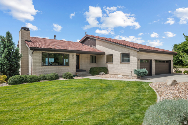 4221 Juniper Circle Alpine, UT 84004 - Photo 44 of 66 Exterior featuring light-colored brick, a red tile roof, a prominent brick chimney, and an attached two-car garage with brown doors