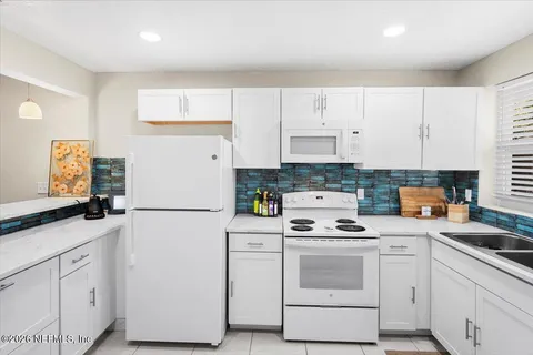 a kitchen with white cabinets and white appliances
